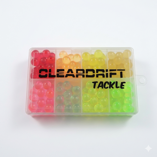 A clear 8-compartment tackle box filled with various colors of Cleardrift soft beads, including red, yellow, and chartreuse, featuring the Cleardrift Tackle logo on the lid.